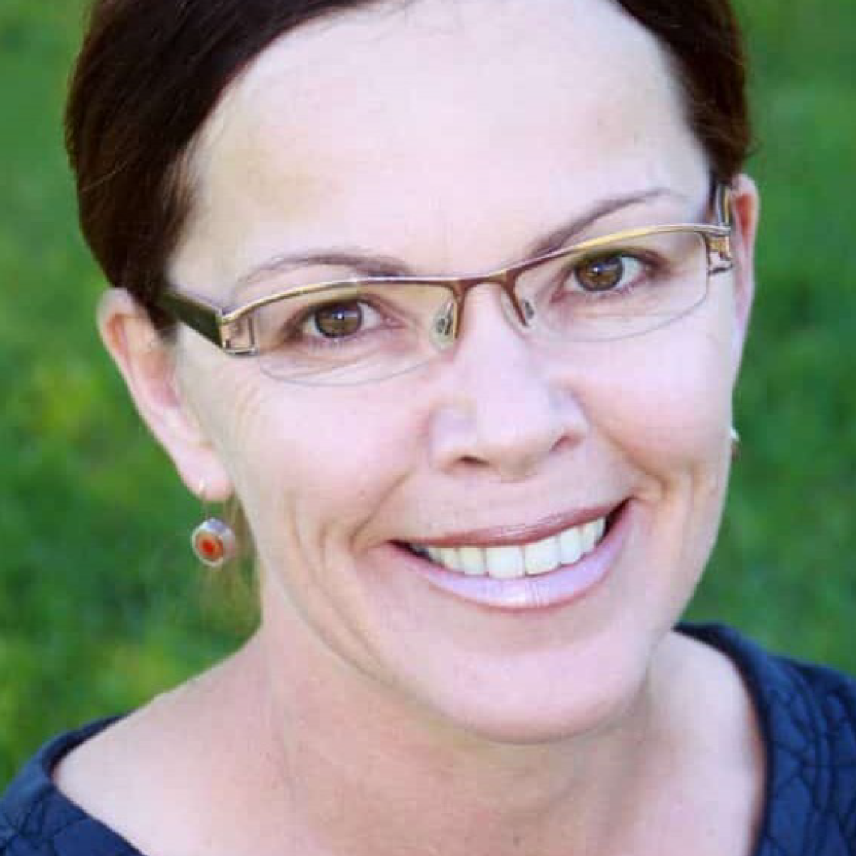 Woman wearing glasses with a blurred green background